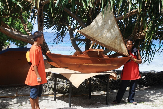 Graduates pose with a large scale model canoe at the graduation.