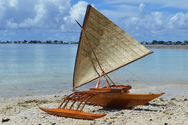 A model canoe, measuring three feet, made by WAM trainees sits on the beach next to the Canoe House.