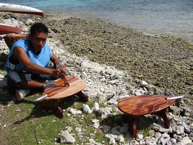 A WAM trainee finishes off a coconut grater with a coat of varnish.